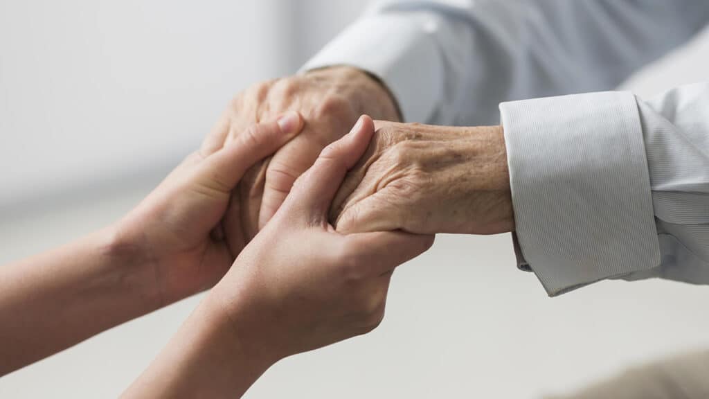 caretaker holding hands with elderly